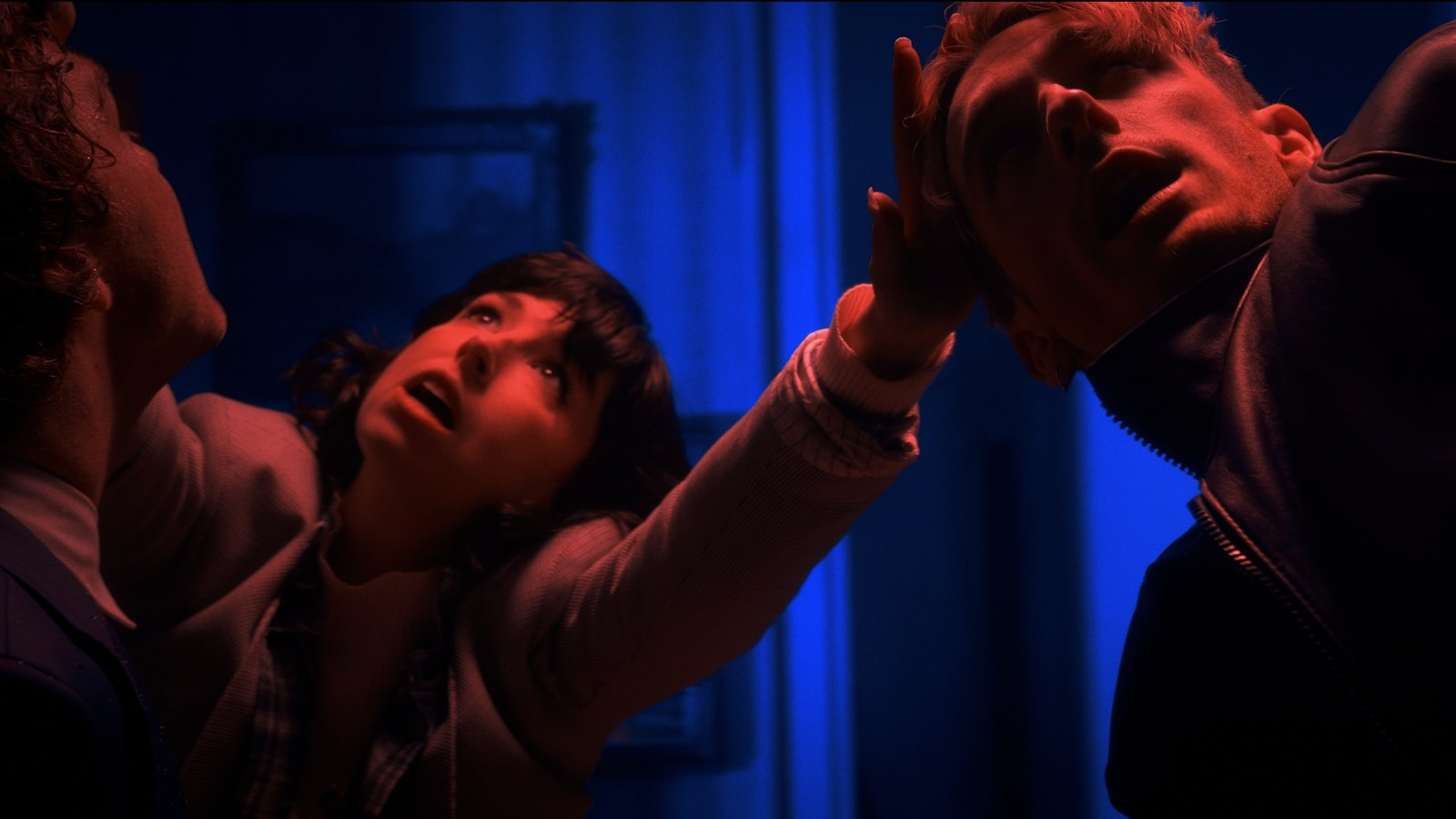 Raised hands in a crowd under red and blue light