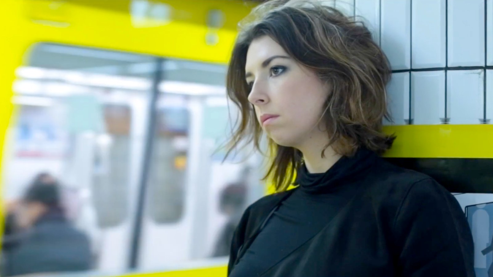 A woman waiting beside a yellow train carriage