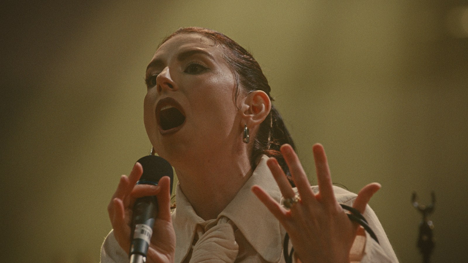 A vocalist mid-phrase, hands raised