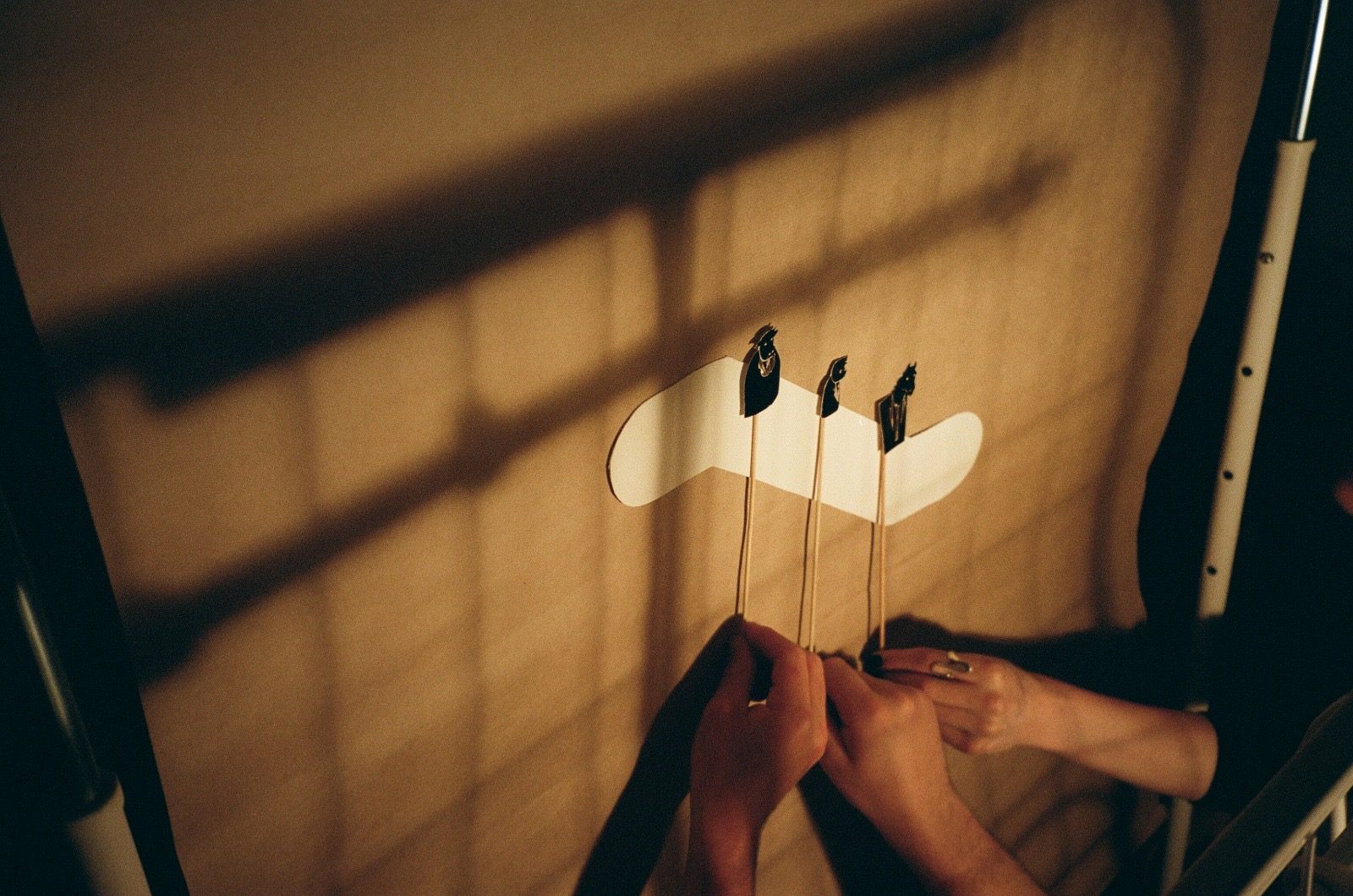 Hands operating cut-paper puppets on sticks behind the screen